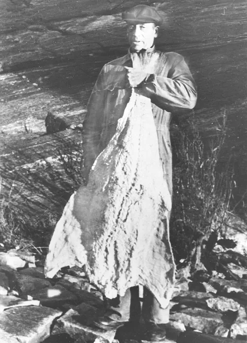 Black and white photo of the founder holding a large clipfish